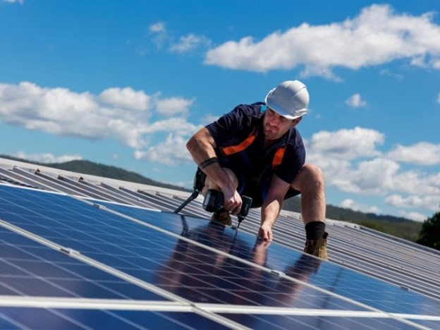 A man working on the roof of a solar panel.